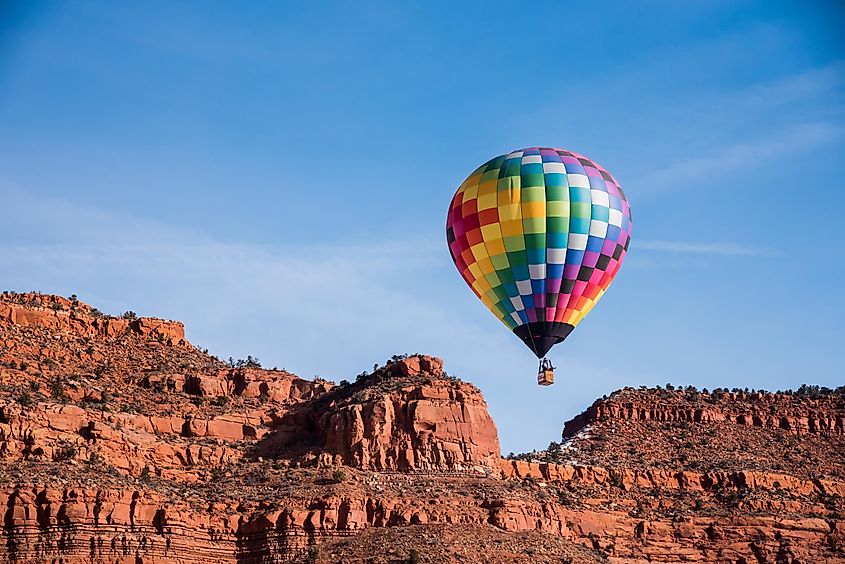 Colorful balloons contrast with red rock cliffs during the annual Balloons and Tunes Festival in Kanab, Utah, USA.