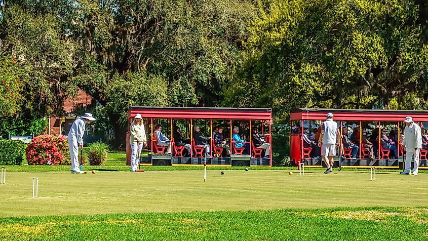 Tourists ride a trolley past Jekyll Island Croquet Club members during a leisurely match on the Greensward in front of historic resort Jekyll Island Club