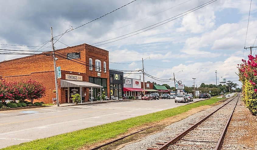 The Main Street, showing buildings, railroad track, and water tower in the distance in Hudson, North Carolina.