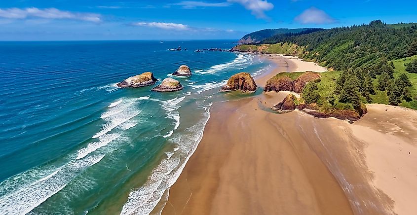 Aerial panorama shot at approximately 350 feet above Cannon Beach, looking towards Ecola State Park on a sunny day with a blue sky on the Oregon Coast.