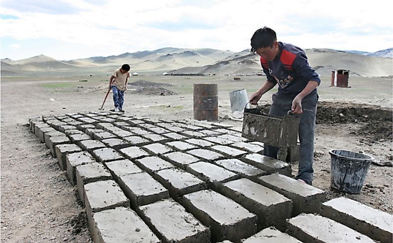 Two Mongolian boys prepare a brick for construction of a house in Mongolia.
