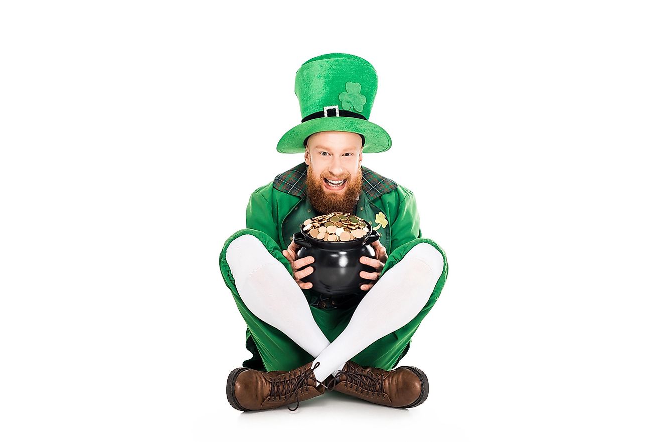 A man dressed as a leprechaun in green suit holding a pot of gold.