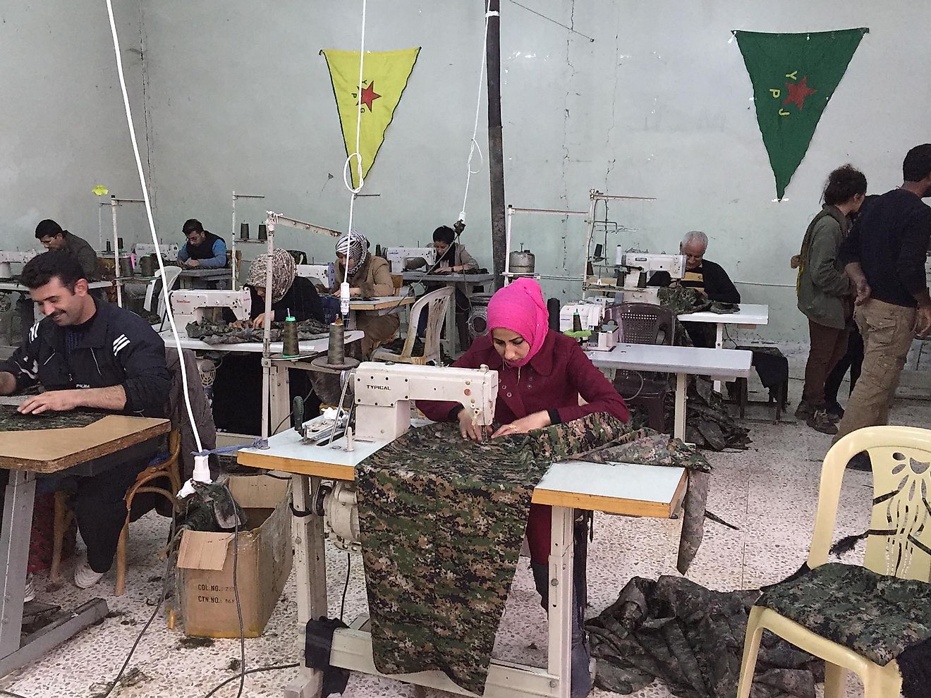 Syrian men and women sewing garments at a cooperative for workers.