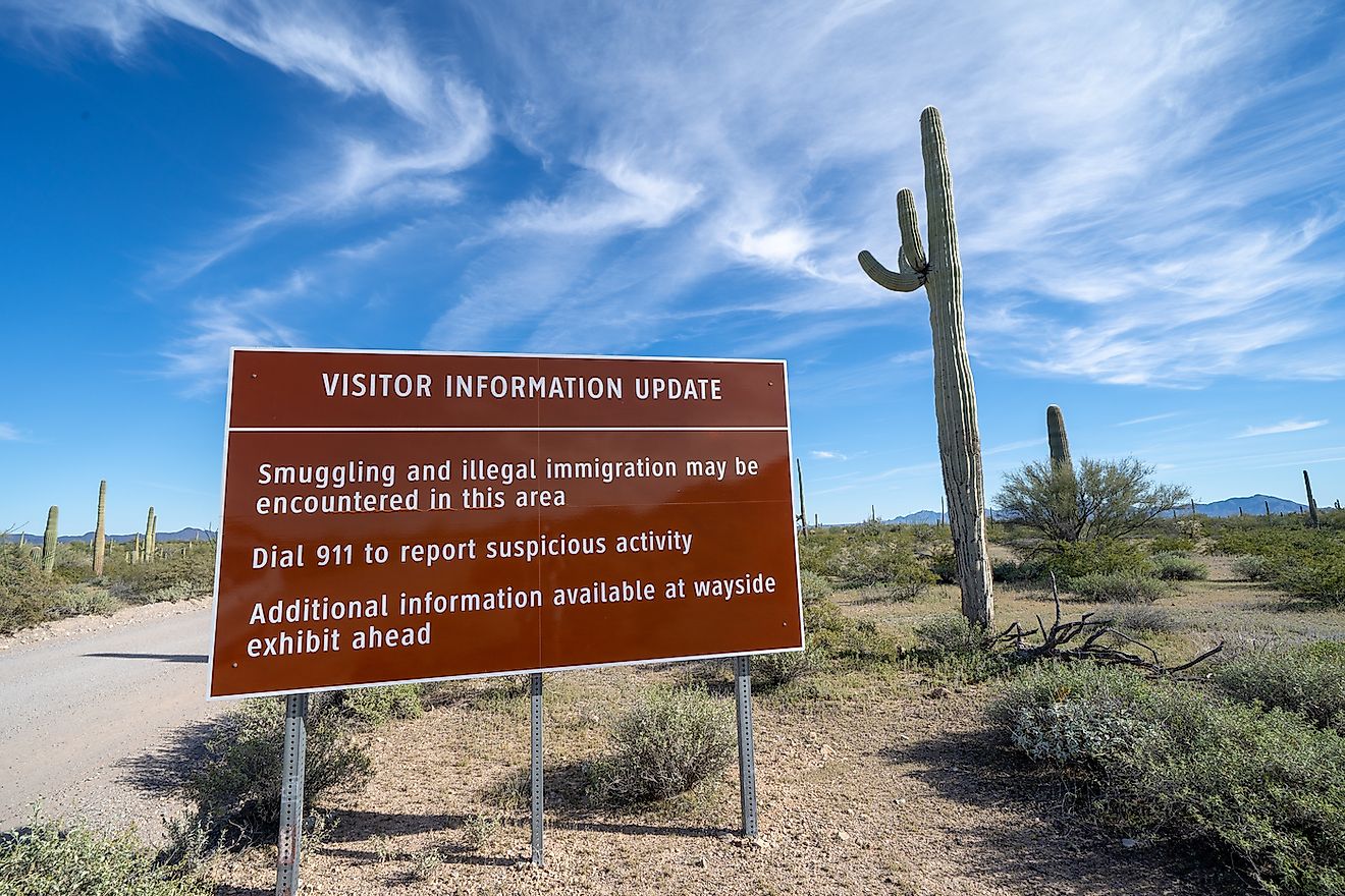 Sign at Organ Pipe National Monument, near the US and Mexico border, warns visitors to be aware of drug cartels and illegal immigration in the area. Image credit: Melissamn/Shutterstock.com