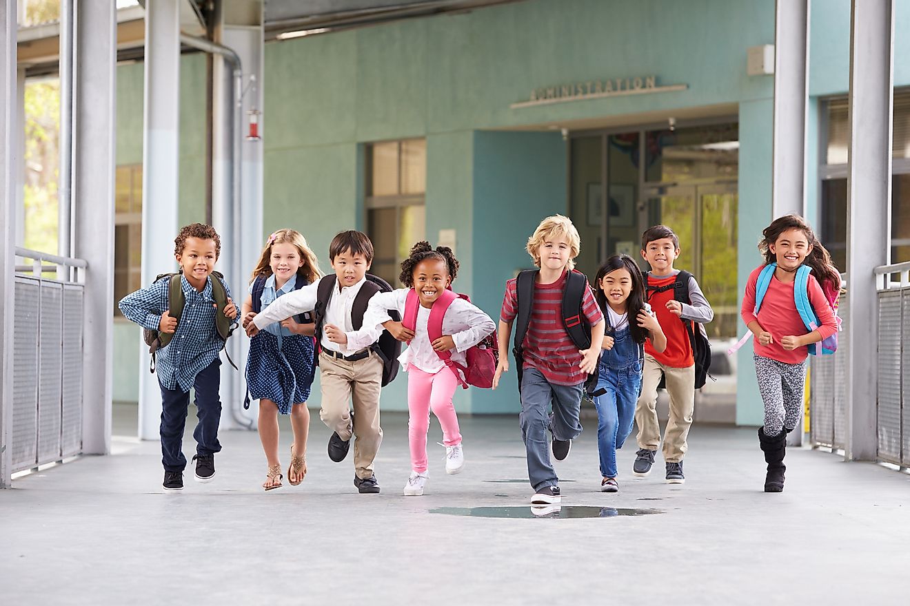 Group of elementary school kids in the US running in a school corridor.