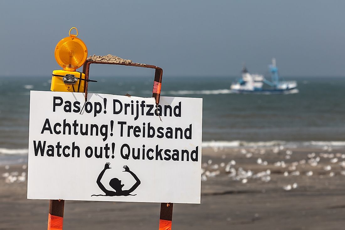 A sign warning of the danger of quicksand in multiple languages. 