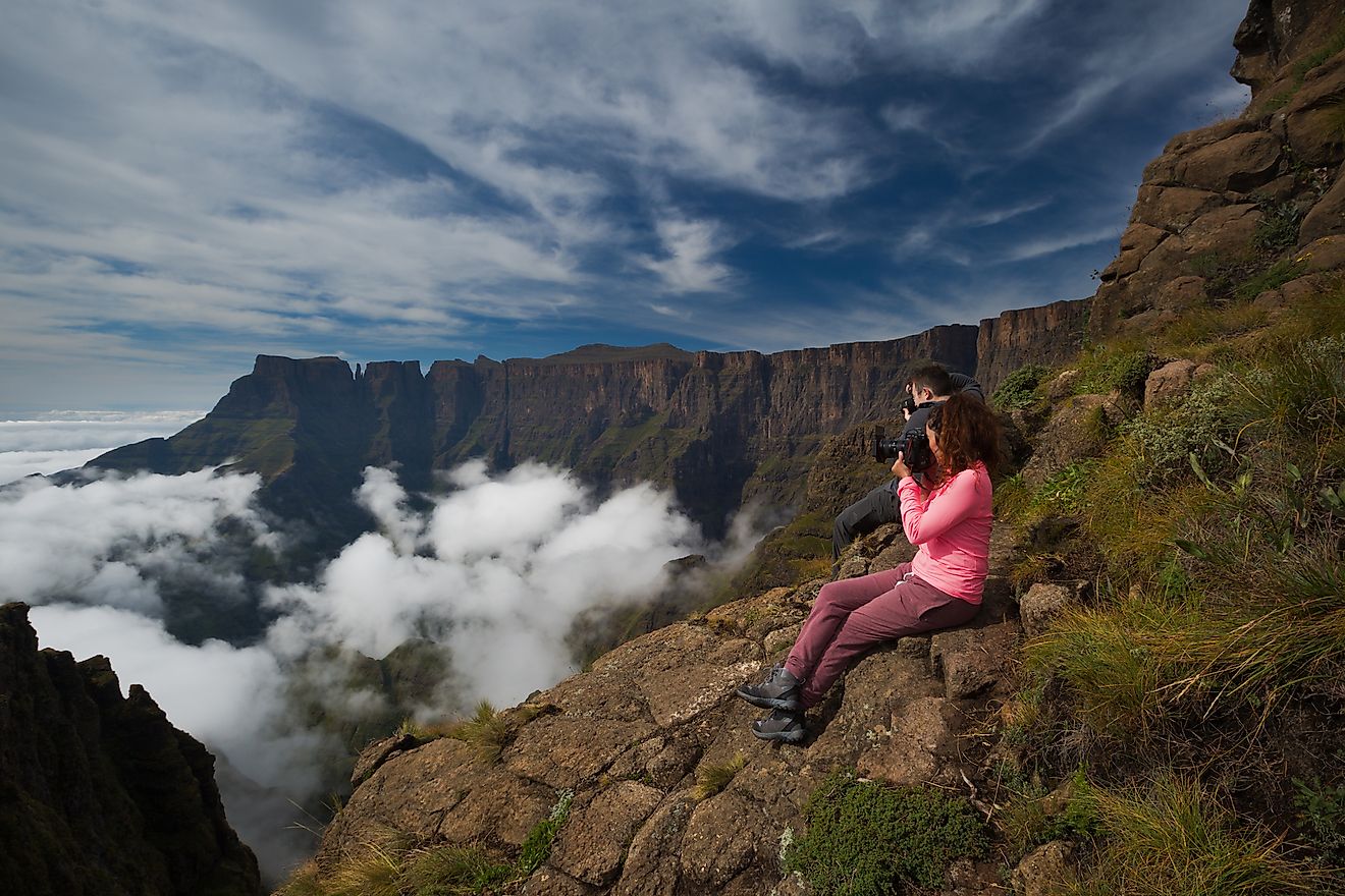 Two photographers photograph the beauty of the Drakensberg Amphitheatre from the Witches Viewpoint in the Ukhahlamba Drakensberg Park, South Africa. Image credit:  Rudi van den Heever/Shutterstock.com