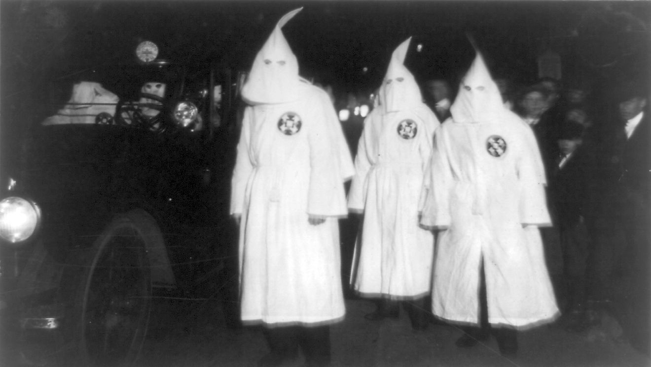 Three Ku Klux Klan members standing beside automobile driven by Klan members at a Ku Klux Klan parade through counties in Northern Virginia bordering on the District of Columbia. Image credit: National Photo Company Collection