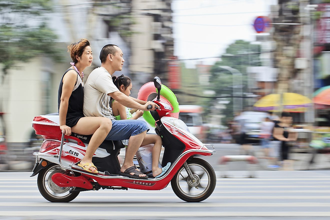 Chinese couple with their child on a scooter. Image credit: TonyV3112 / Shutterstock.com