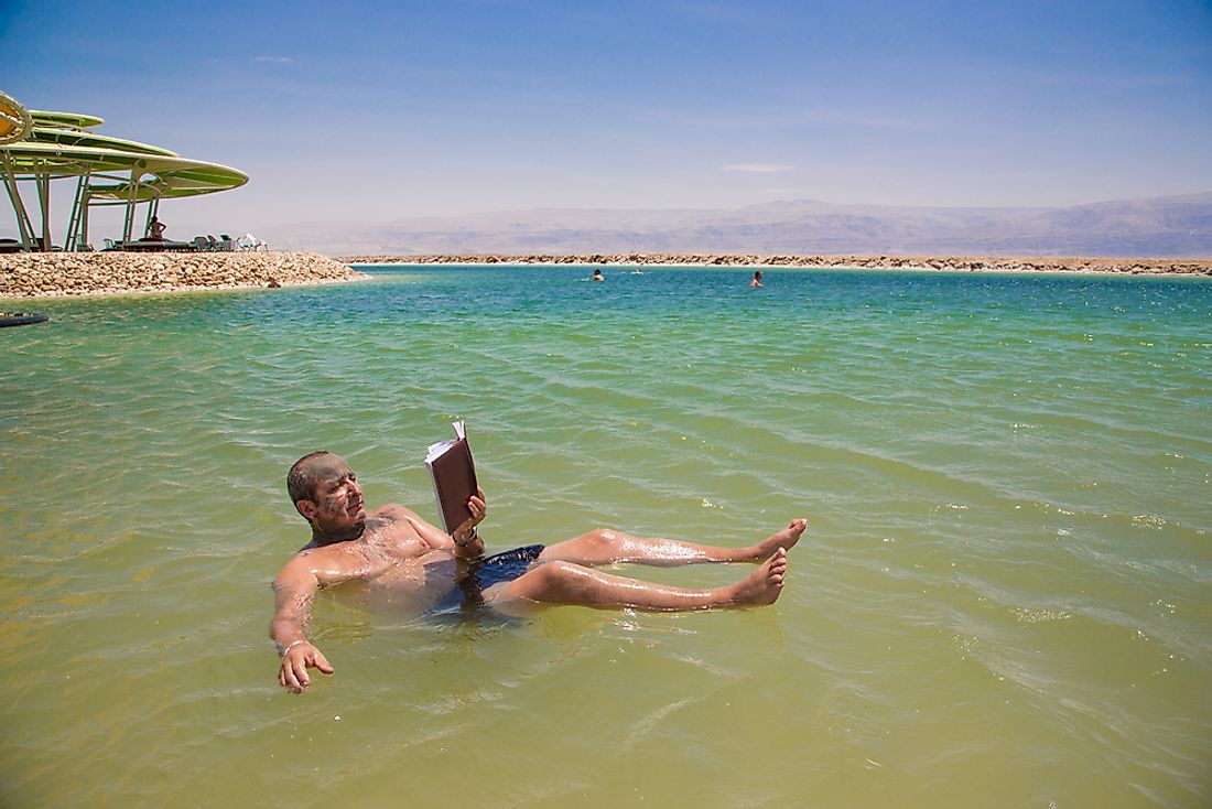 A man floating on the Dead Sea and reading a book.