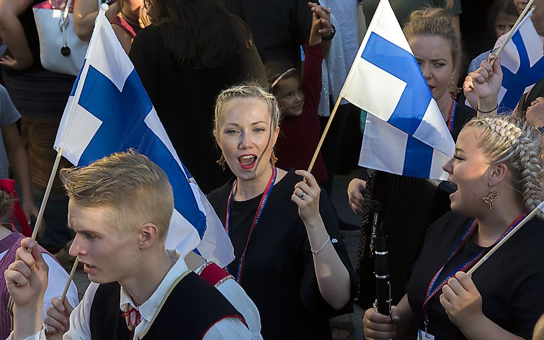 Dancers hold Finnish flags at the Royal Days International Folk Dance Festival. Editorial credit: Andocs / Shutterstock.com.