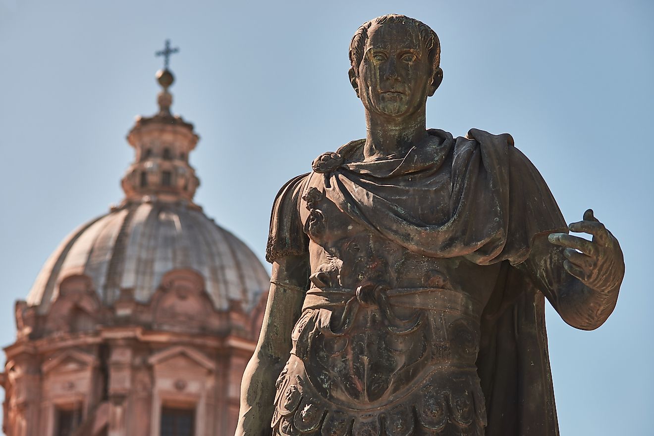 Bronze statue of emperor Julius Caesar, the dome of Saints Luca and Martina Church in the background. Image credit: Di Gregorio Giulio/Shutterstock.com