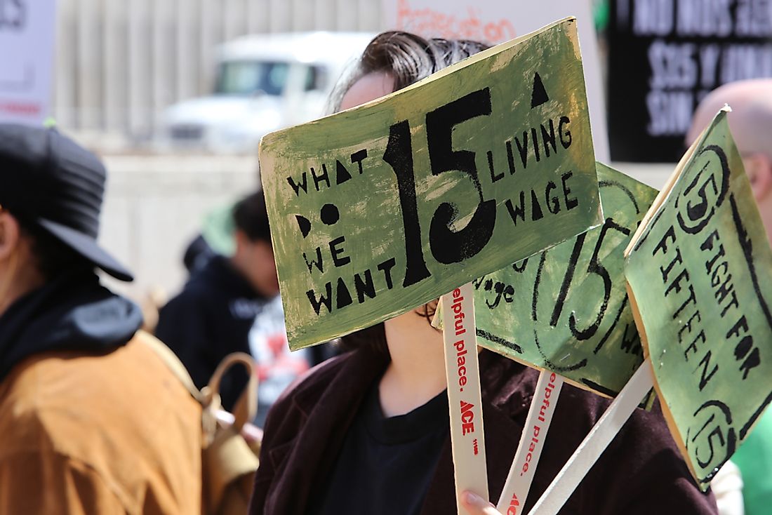 A protestor holds signs at a march for a $15 per hour federal minimum wage. Editorial credit: a katz / Shutterstock.com.