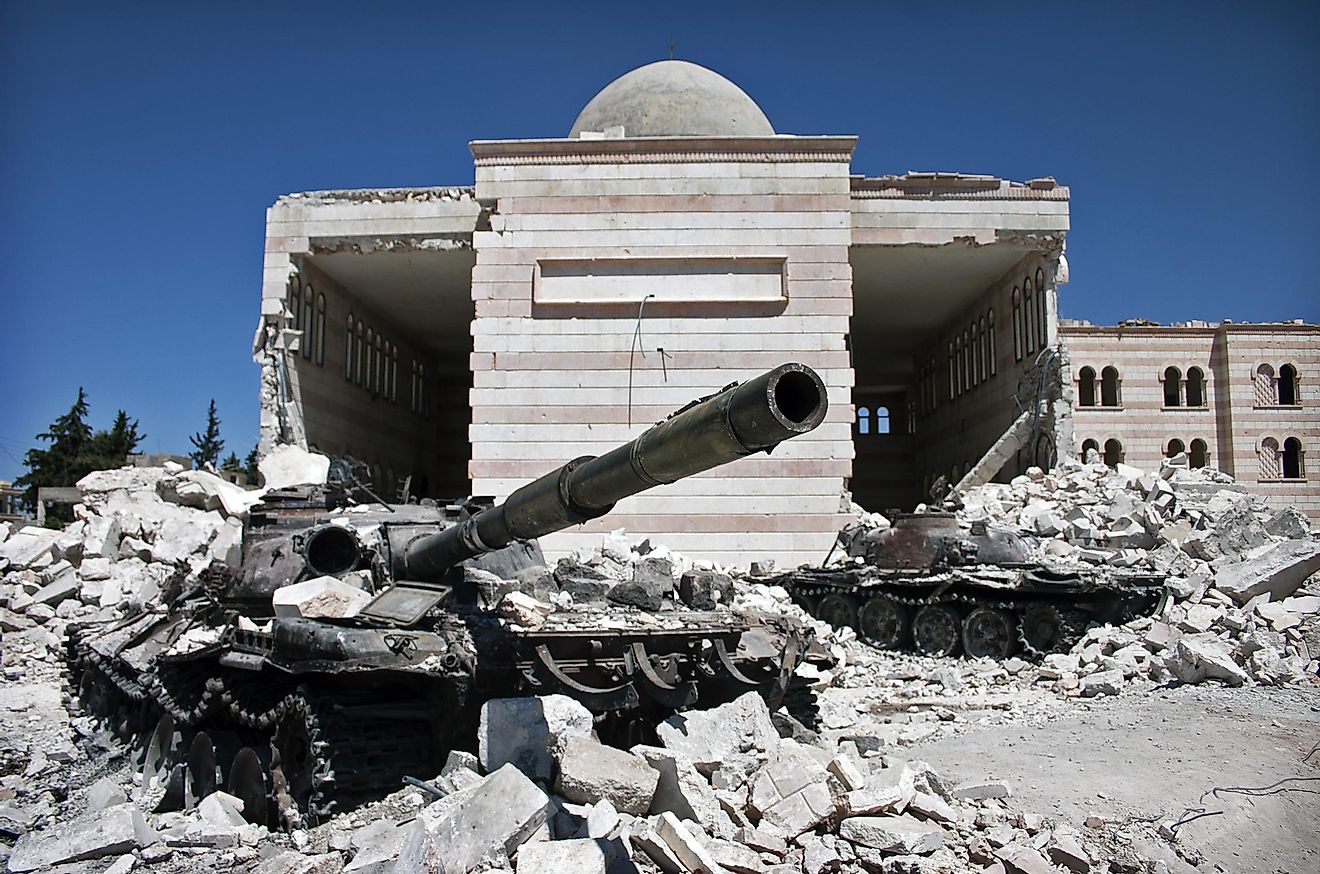 A tank sits in front of a mosque that has been destroyed by civil war in Syria. Editorial credit: Christiaan Triebert / Shutterstock.com. 