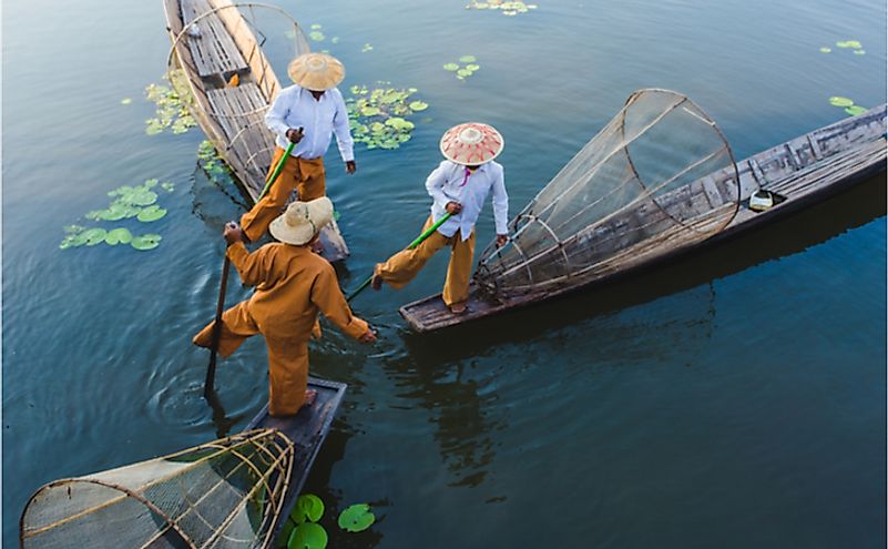 Burmese fishermen on Inle Lake stand on one leg while fishing, a unique skill developed over generations.