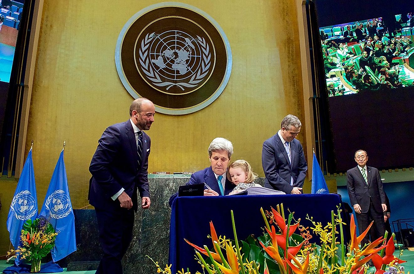 Secretary Kerry Holds Granddaughter Dobbs-Higginson on Lap While Signing COP21 Climate Change Agreement at UN General Assembly Hall in New York on Earth Day, April 22, 2016,. Image credit: U.S. Department of State from United States/Public domain.