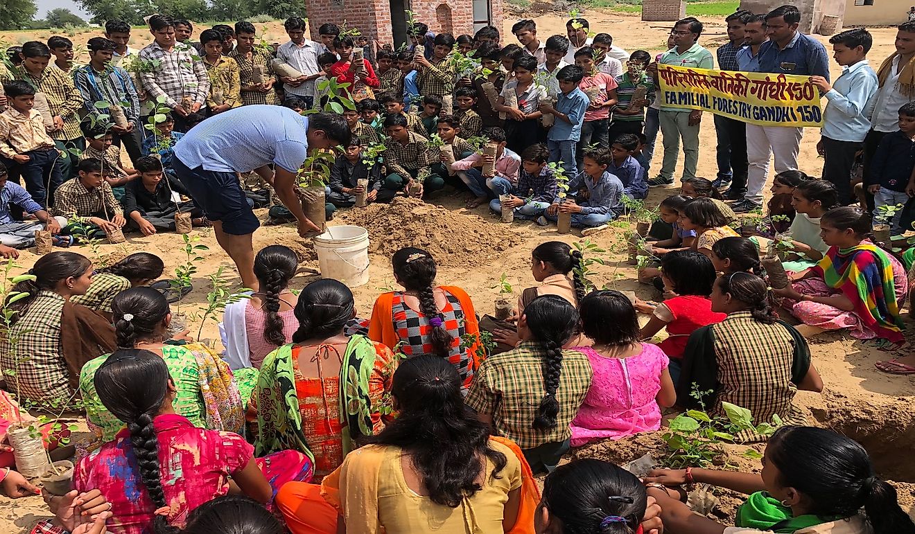 Jyani demonstrating a sapling planting technique to the children.