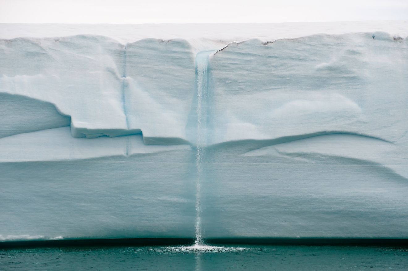 Melting ice forms waterfall falling into sea over edge of glacier wall due to global warming in Northern Arctic. Image credit: Tony Skerl/Shutterstock.com