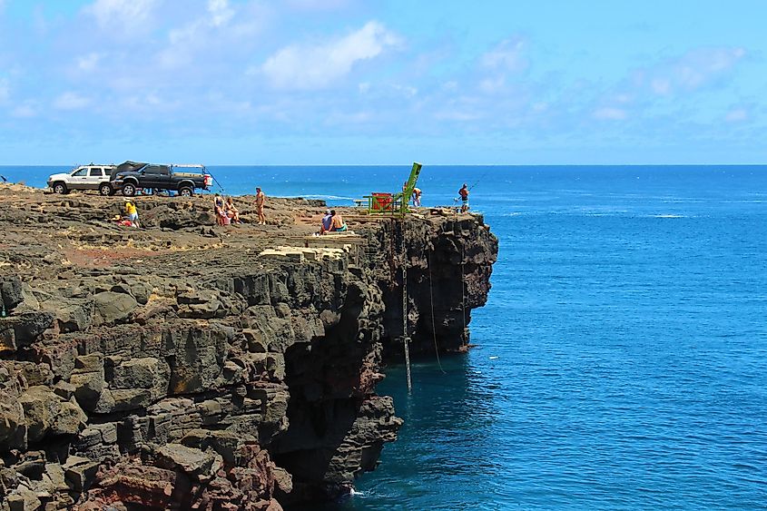 Tourists and local fishermen gather on the cliffs of South Point on a warm day to enjoy the Hawaiian sunshine in Naalehu. Editorial credit: Ty King / Shutterstock.com