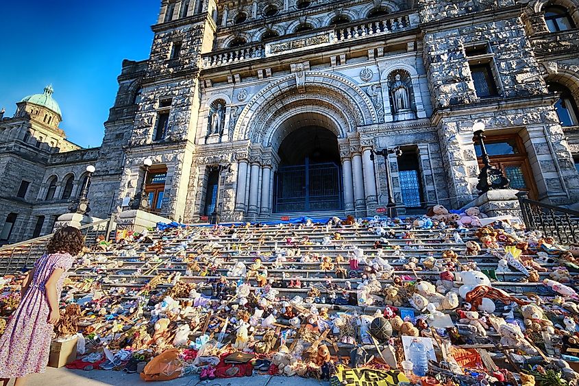  A woman looks at a memorial - shoes, and stuffed toys - honoring the victims of Canadian residential schools on the steps of the BC Legislature.