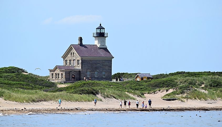 People on the sandy beach at Block Island North Light Lighthouse in New Shoreham, Rhode Island.