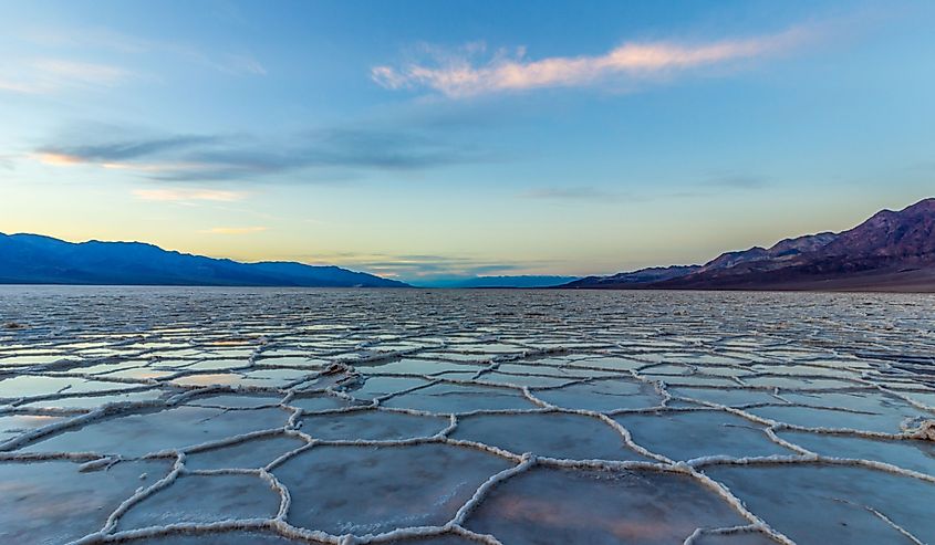Badwater Basin at Sunset. Salt Crust and Clouds Reflection. Death Valley National Park.