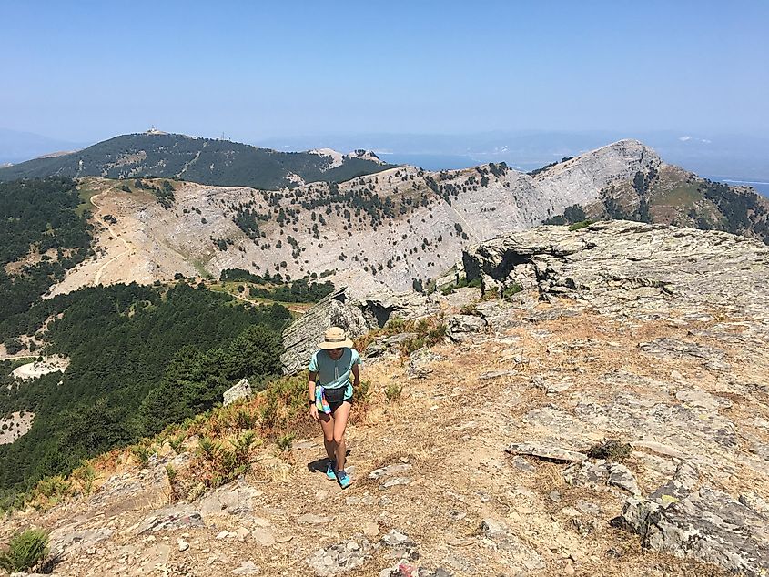 A hiker nears the summit of a sun-soaked mountain in the Mediterranean