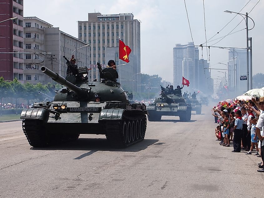 Military tanks parade in front of waving crowds through the streets of Pyongyang, North Korea