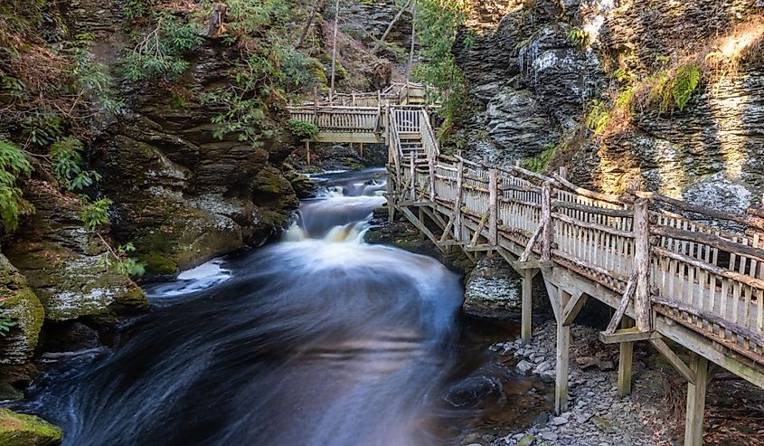 Winding wooden boardwalk across a flowing river and small waterfalls, Bushkill Falls, Pennsylvania