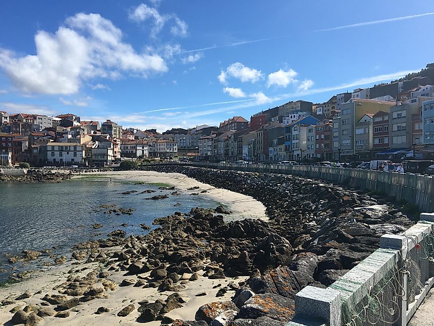A seaside town in Northwestern Spain. Colorful buildings stand next to the rocky/sandy Atlantic Coast.