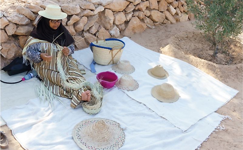 Arab woman engaged in weaving straw wide brim hat in Tunisia. Editorial credit: Pavel Kosolapov / Shutterstock.com