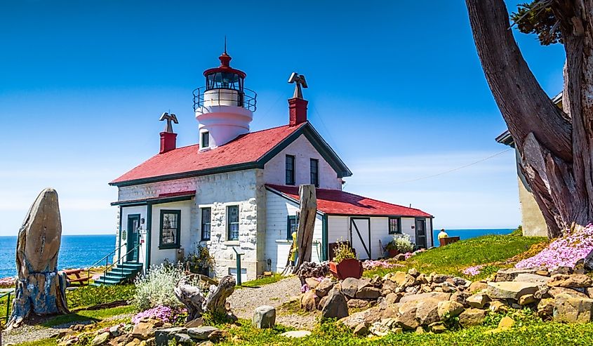 Battery Point Lighthouse in Crescent City California, green grass, colorful flowers, blue sky on a sunny day