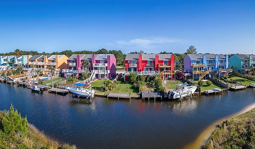 Facade of colorful houses along the bay in Navarre Florida scenic community. Panoramic view of a waterfront neighborhood with small boats docked in front of the homes.