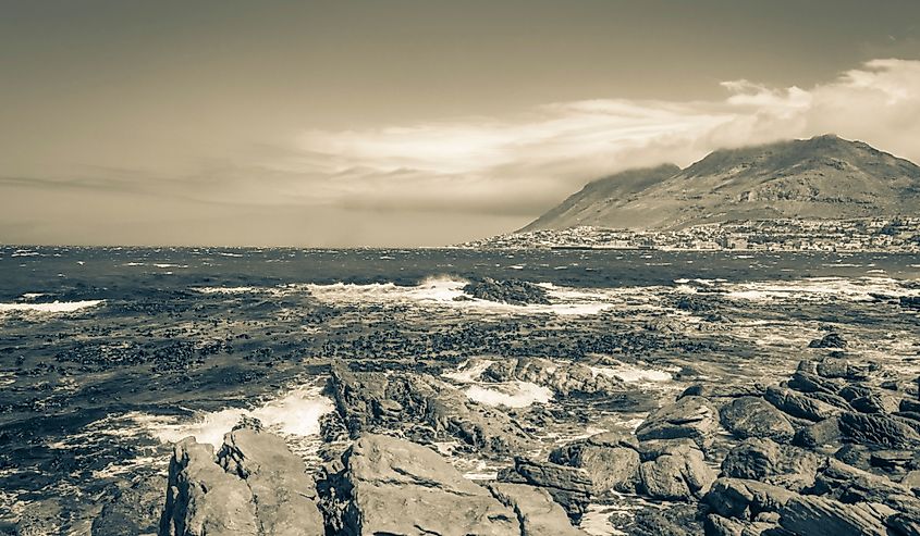 False Bay rough coast landscape with boulders waves and mountains with clouds in Glencairn Simons Town Cape Town Western Cape South Africa.