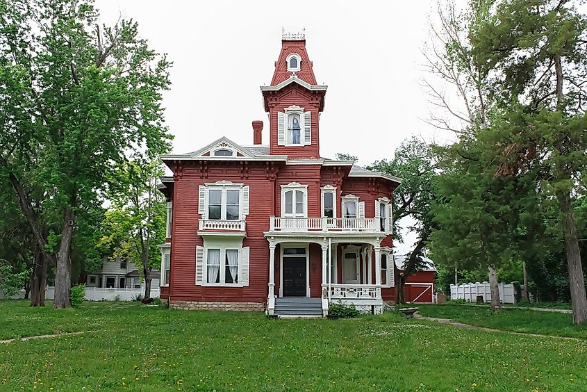 Red historic mansion with a mansard roof in Abilene, Kansas, with a spooky figure in the upstairs window.