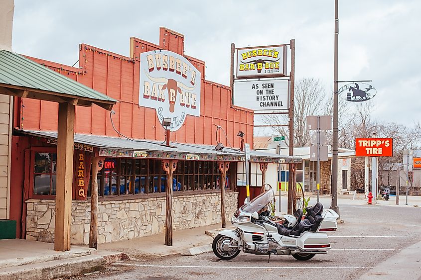 Bandera, Texas - Shops and signs set against the backdrop of a scenic road with cars and bikes.