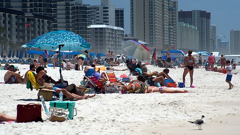 Crowd of tourists under colorful beach umbrellas in Panama City Beach, Florida.