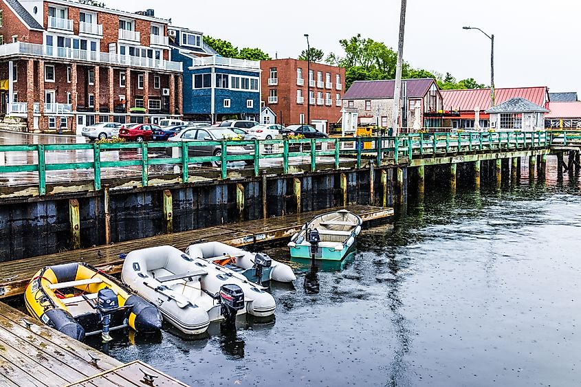 Wooden marina harbor in Castine, USA, during rain, featuring boats and a parking lot in the small village of Maine