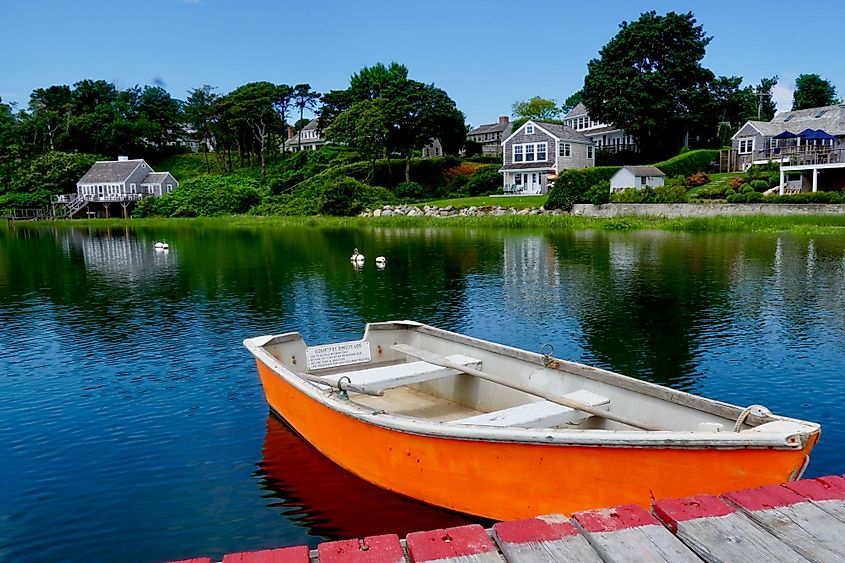 An orange rowboat quietly awaits its turn to sail from the dock where it is tied in Little Mill Pond, Chatham, Massachusetts. 