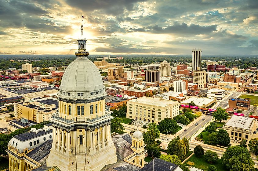 Aerial view of Illinois State Capitol dome and Springfield skyline under a dramatic sunset