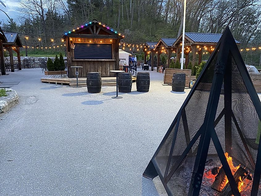An extensive outdoor patio area with lights strung up and a fire pit blazing in the foreground