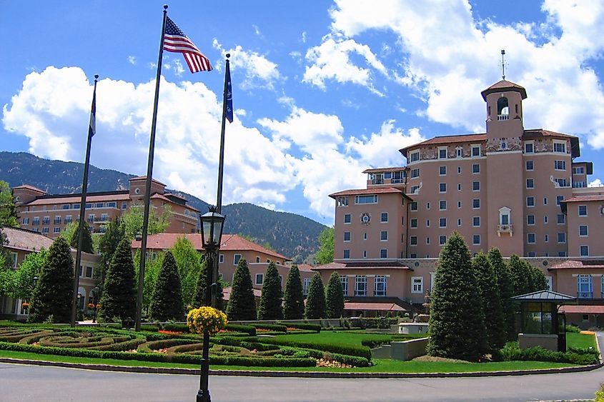 The Broadmoor Resort Italian Renaissance main building and entrance landscaping from Lake Avenue under bright sky. 