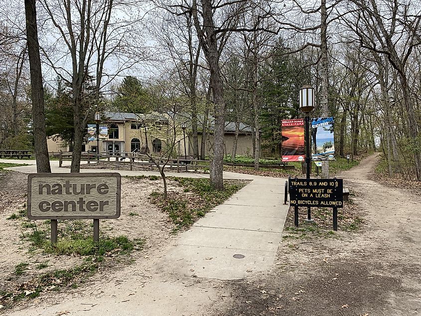 A sign showing the nature Center of Indiana Dunes State Park and another indicating the trail system 