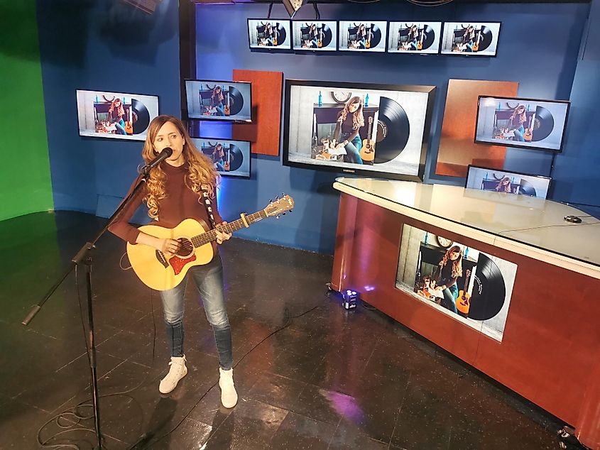A female musician playing guitar on a local TV studio