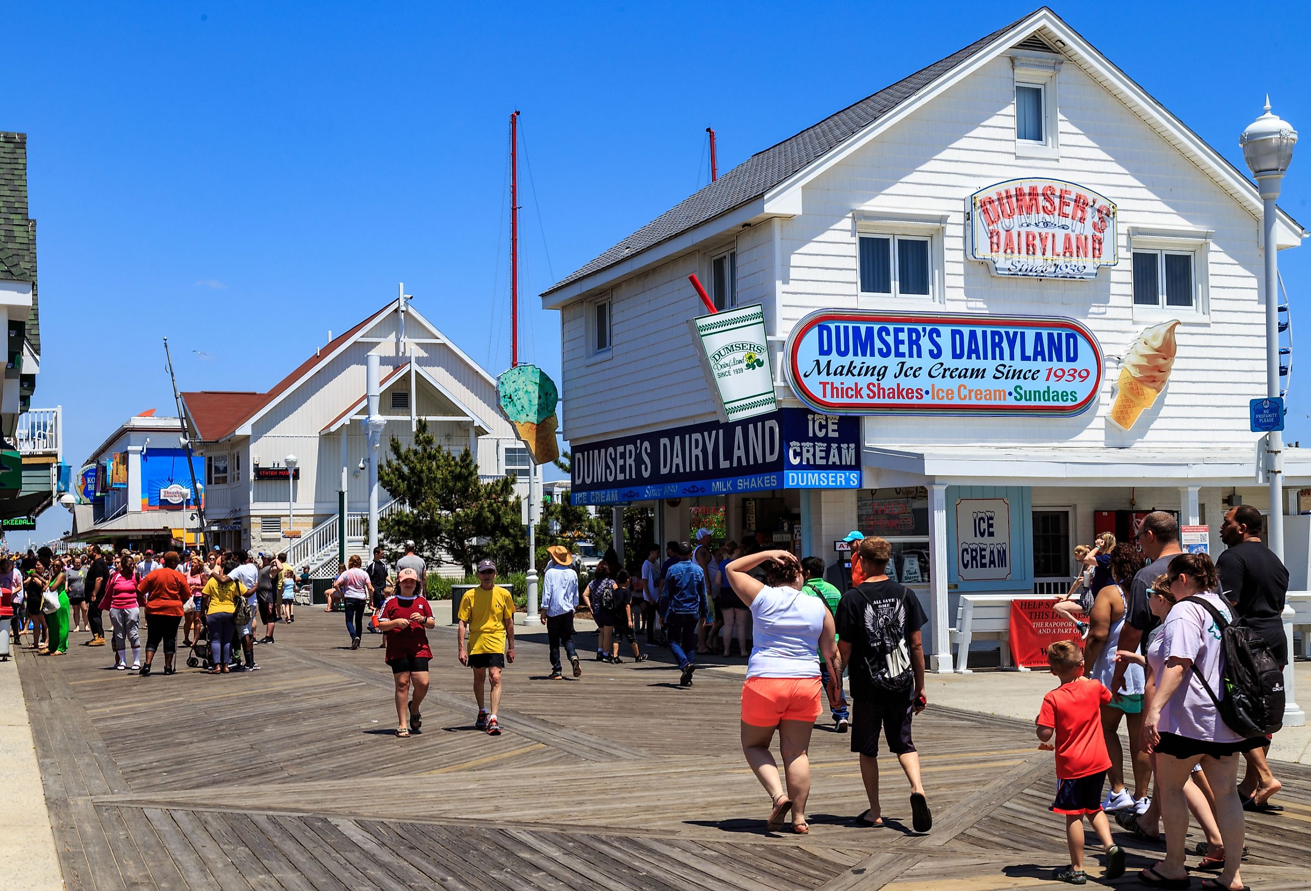 Stores, shops, and eateries attract visitors on the Ocean City boardwalk, Maryland. Image credit George Sheldon via Shutterstock