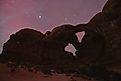 Rare aurora borealis dancing above Double Arch in Arches National Park, Utah - an extraordinary celestial event over iconic southwestern landscape