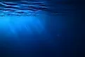 Underwater view of the ocean with rays of sunlight filtering through blue water