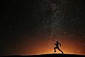 Runner athlete running on the hill with beautiful starry night background.