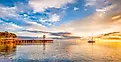 A boat anchored on the calm waters of the Puget Sound as the early morning sun rays warm the cloud ridden sky at Port Angeles, Washington.