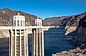 Detailed view of the Hoover Dam intake towers standing above the Colorado River, showing water levels and surrounding rocky desert terrain